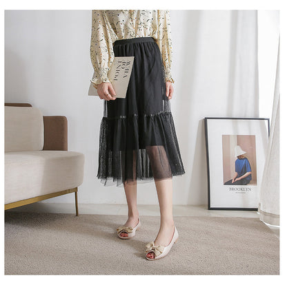Femme portant des mules noires plates à nœud sur tapis beige disponible chez luxorel.