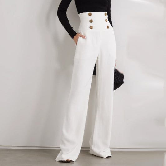 Femme portant un pantalon taille haute à jambe large, avec double rangée de boutons dorés esprit officier – disponible en noir et blanc chez Luxorel

