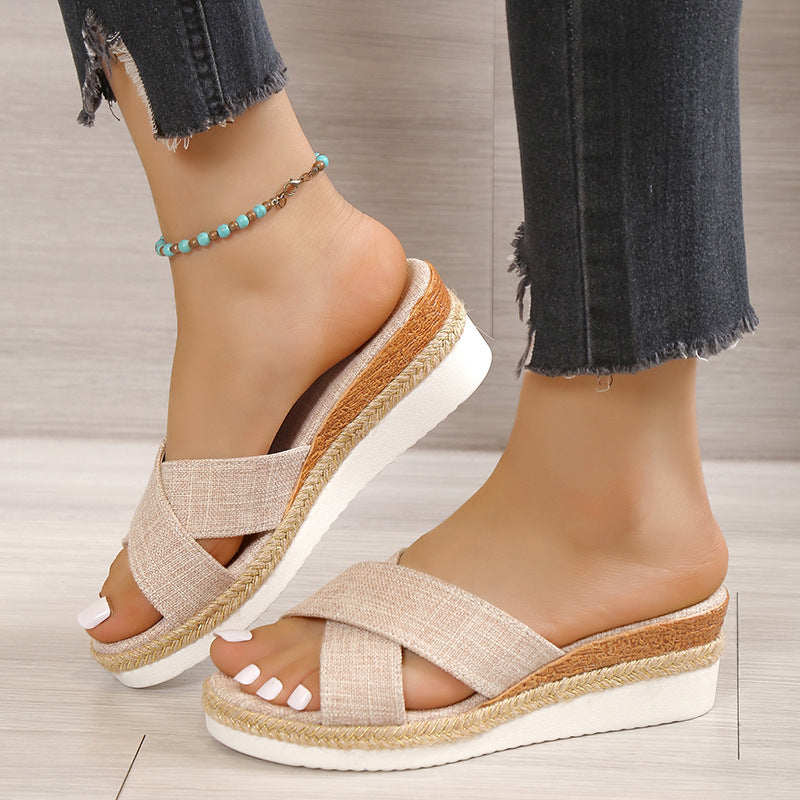 Femme portant des mules compensées à brides croisées, semelle tressée façon espadrille, disponibles en beige, noir, marron et blanc – modèle estival confortable chez Luxorel