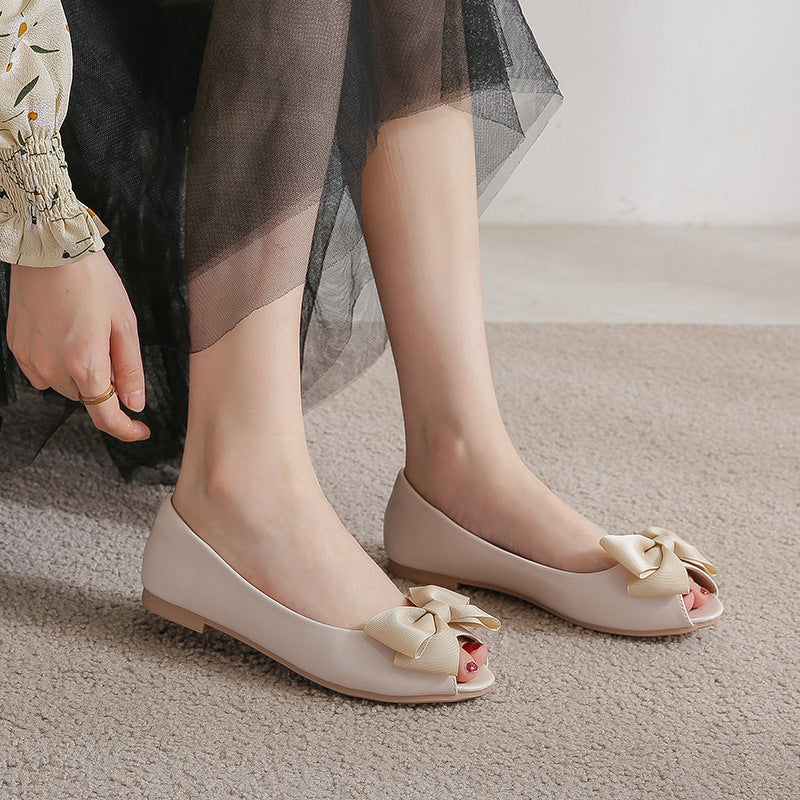 Femme portant des mules noires plates à nœud sur tapis beige disponible chez luxorel.