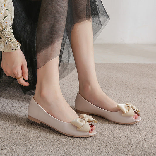 Femme portant des mules noires plates à nœud sur tapis beige disponible chez luxorel.