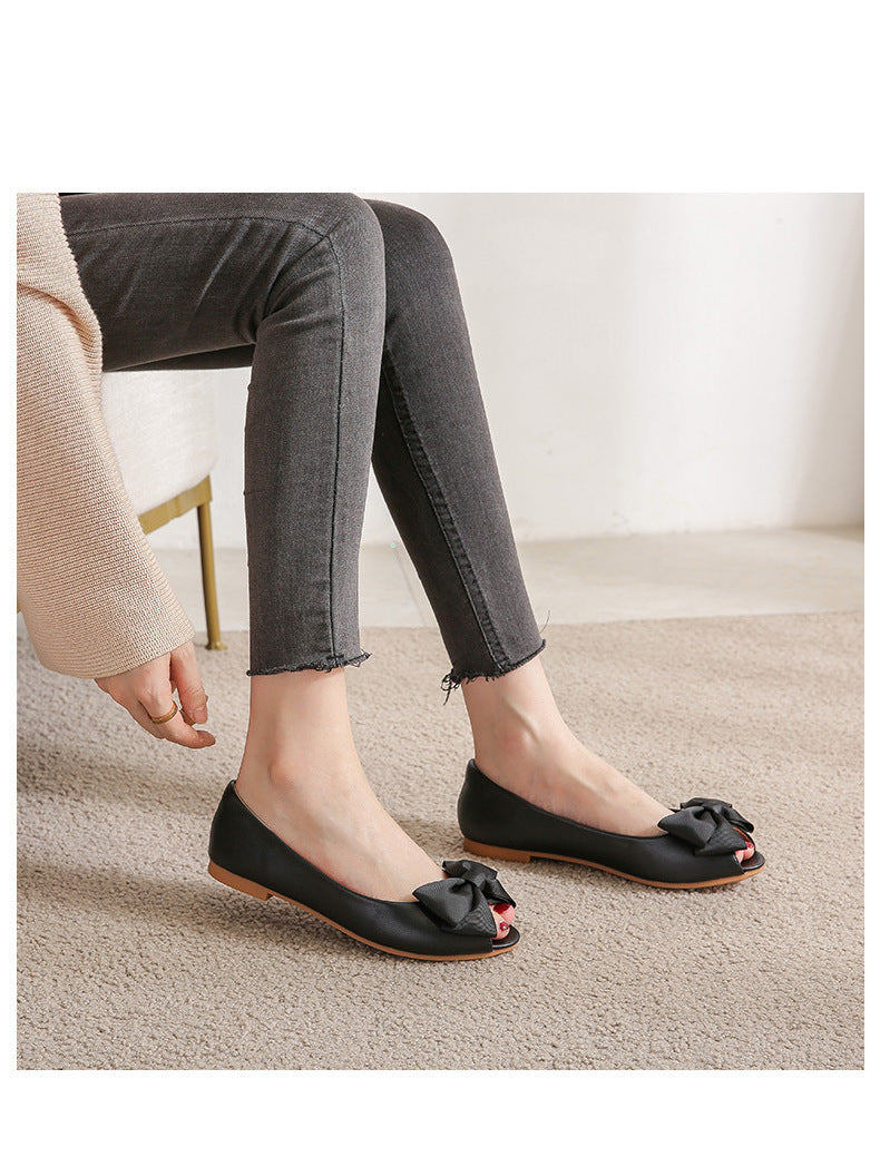 Femme portant des mules noires plates à nœud sur tapis beige disponible chez luxorel.